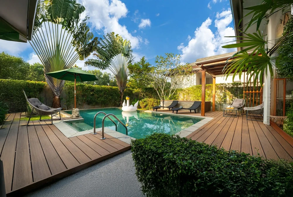 Scène extérieure d'un jardin avec spa circulaire en bois installé sur terrasse en lames de bois composite